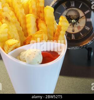 Un top bianco con patatine fritte, ketchup e maionese, primo piano Foto Stock