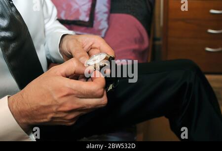 Orologio che è impostato da un uomo in una camicia e cravatta. Foto Stock