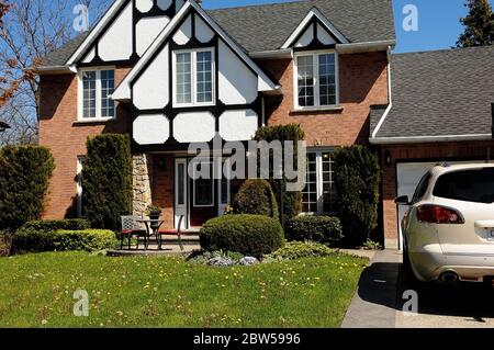 Un'immagine ravvicinata di una bella casa vecchia in una giornata di sole con un bel prato anteriore e una macchina nel modo di guida Foto Stock