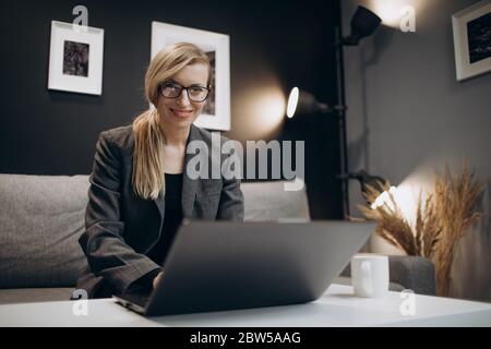 Donna attraente in tuta alla moda che lavora con il laptop Foto Stock