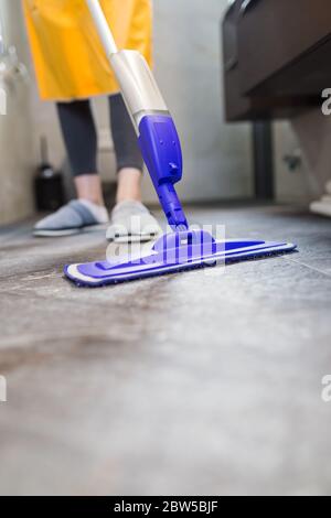 Cameriera fare chores a casa tenendo il bastone di pulizia. Concetto di prevenzione del coronavirus. Foto Stock