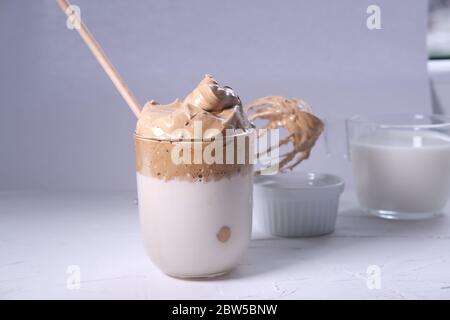 Caffè Dalgona con caffè montato e latte sullo sfondo. Caffè coreano freddo e soffice. Foto Stock