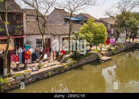 Tongli, Jiangsu, Cina - 3 maggio 2010: Primo piano di linee di asciugatura colorata lavanderia lungo il canale verde acqua sotto il cielo azzurro con verde fogliame e. Foto Stock