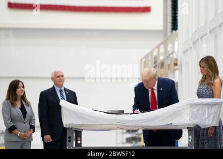 Il presidente Donald Trump firma un pannello di capsule Orion mentre guarda First Lady Melania Trump, durante un tour delle capsule spaziali dell'equipaggio commerciale Orion presso il Kennedy Space Center Operational Support Building 27 maggio 2020 a Cape Canaveral, Florida. Da sinistra a destra ci sono: Karen Pence, Vice Presidente Mike Pence, Presidente Donald Trump e First Lady Melania Trump. Foto Stock