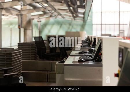 Fila di banchi di check-in con monitor di computer presso il terminal dell'aeroporto vuoto a causa di una pandemia di coronavirus/epidemia di Covid-19. Messa a fuoco selettiva. Divieto di viaggio. Foto Stock