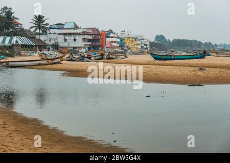 Barche da pesca sparse in una giornata nuvolosa sulla spiaggia di Mahabalipuram, India Foto Stock