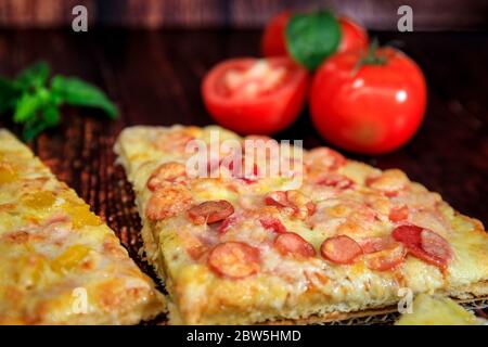 Pizze da closeup con cabanossi, prosciutto e formaggio su fondo di legno marrone Foto Stock