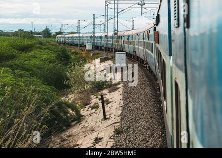 La vista delle carrozze dalla porta del treno come si arrotonda una curva che si avvicina Madurai, Tamil Nadu, India Foto Stock