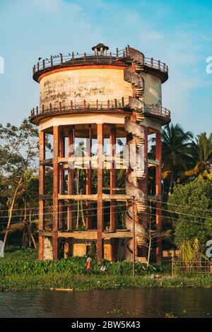 Una torre d'acqua in cemento vista lungo le rive del backwaters in Kerala, India Foto Stock