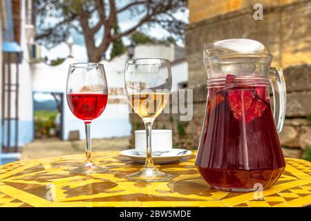 Brocca di sangria con vetri rossi e bianchi su un paesaggio spagnolo offuscato in Spagna. Foto Stock