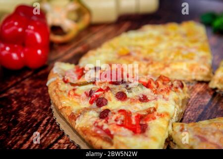 Primo piano di una fetta di pizza casalinga, carnosa e piccante, con salsiccia calda, salame e mozzarella Foto Stock