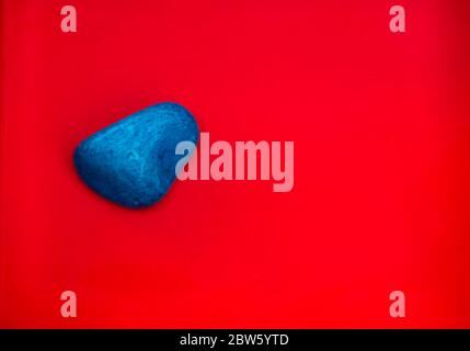 Colore blu Pebbles naturali isolati su sfondo rosso con spazio per copiare testo e parole. Pietra naturale multicolore. Pietra di colore blu isolata Foto Stock