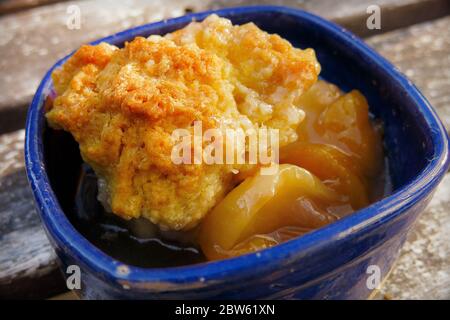 Primo piano di Peach e Biscuit Dessert in Blue Bowl Foto Stock