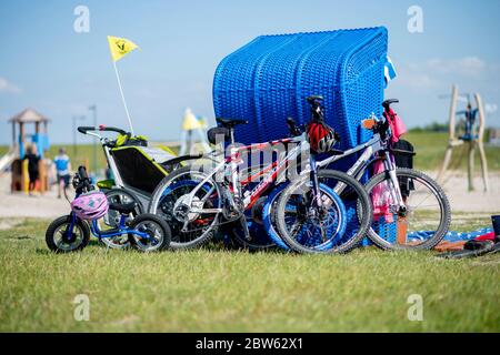 Tossens, Germania. 29 maggio 2020. Le biciclette di una famiglia sono appoggiate su una sedia blu sulla spiaggia di Friesenstrand, nel quartiere di Wesermarsch. A Whitsuntide, numerosi turisti sono attesi sulla costa della bassa Sassonia, le isole e altrove. Credit: Hauke-Christian Dittrich/dpa/Alamy Live News Foto Stock