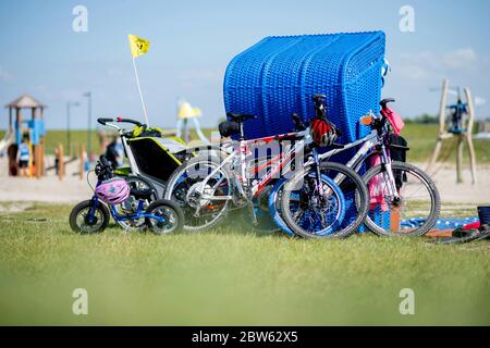 Tossens, Germania. 29 maggio 2020. Le biciclette di una famiglia sono appoggiate su una sedia blu sulla spiaggia di Friesenstrand, nel quartiere di Wesermarsch. A Whitsuntide, numerosi turisti sono attesi sulla costa della bassa Sassonia, le isole e altrove. Credit: Hauke-Christian Dittrich/dpa/Alamy Live News Foto Stock