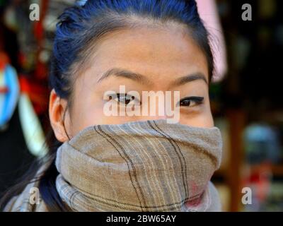 Giovane Angami indiano con occhi belli copre il naso e la bocca con una sciarpa protettiva. Foto Stock