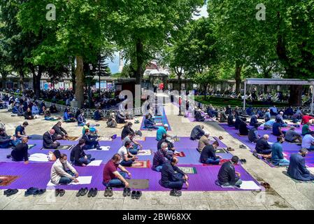 Pregare con maschere mediche fuori della Moschea Blu. Il primo venerdì pregate, namaz dopo la chiusura a Istanbul. I musulmani pregano insieme per la guarigione Foto Stock