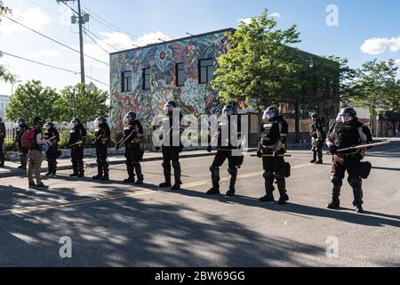 uomo che affronta ufficiali di polizia di pattuglia dello stato in piedi di guardia contro le rivolte di minneapolis e di controllo dimostranti e manifestanti con club Foto Stock