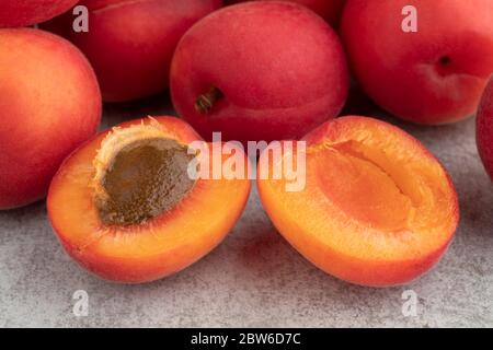 Un primo piano di albicocca di velluto rosso fresco e mezzo maturo con frutta intera sullo sfondo Foto Stock