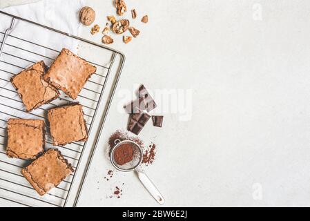 Vista dall'alto della torta di brownie appena sfornata preparata in casa, preparata con ingredienti di ricetta su sfondo rustico bianco. Spazio di copia. Foto Stock