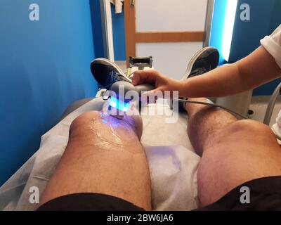 Il fisioterapista sta applicando la terapia a ultrasuoni sulle lesioni al ginocchio con il trasduttore per la testa a ultrasuoni Foto Stock