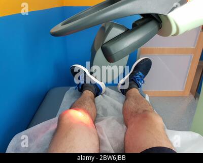 Terapia fisica con un laser per trattare un ginocchio ferito Foto Stock