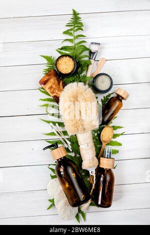 Accessori per il centro benessere - scrub alla noci, spugna, spazzola per il viso, sapone naturale, maschera in argilla, pietra pomice, olio essenziale su sfondo chiaro, vista dall'alto. Sano Foto Stock