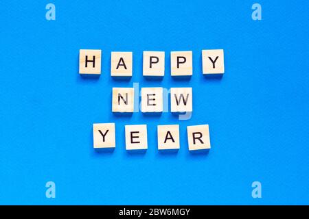 Felice anno nuovo scritto in lettere di legno su sfondo blu. Felice anno 2021. Vista dall'alto. Layout piatto. Spazio per testo. Foto Stock