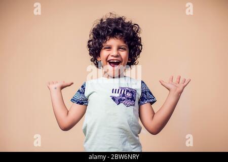 Un ritratto di bambino sorpreso con capelli ricci. Concetto di bambini ed emozioni Foto Stock