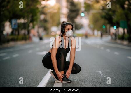 Donna runner con maschera medica. Correre nel parco. Coronavirus pandemico Covid-19. Maschera facciale sterilizzante chirurgica per uso sportivo e attivo in quarantena Foto Stock