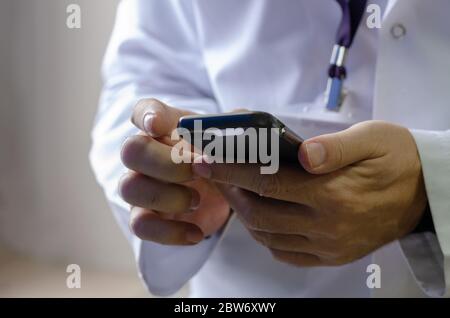 Il medico tiene il telefono in mano e controlla i suoi messaggi Foto Stock