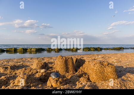 Castello di sabbia con conchiglie in piedi sulla spiaggia. Concetto di vacanza di viaggio. Foto Stock