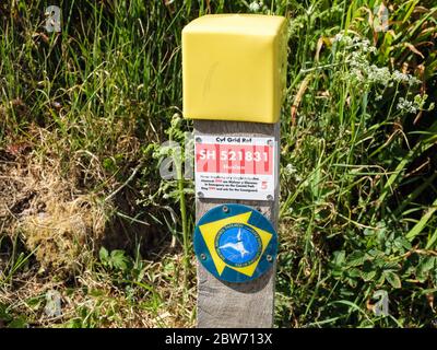 Coastguard riferimento bilingue griglia rossa sul Wales Coastal Path direzione segno waypoint post. Bennlech, Isola di Anglesey, Galles, Regno Unito, Gran Bretagna Foto Stock