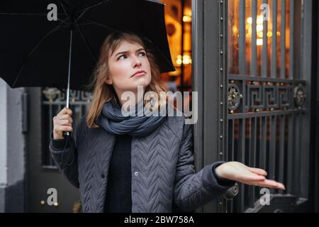 Triste signora in piedi sulla strada con ombrello nero Foto Stock
