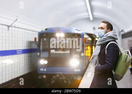 Malato giovane uomo avvolto in sciarpa sensazione di malessere, indossando maschera protettiva contro le malattie infettive trasmissibili e come protezione contro l'influenza in pu Foto Stock