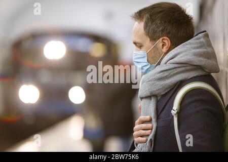 Uomo esausto che si sente malato, indossando una maschera protettiva contro le malattie infettive trasmissibili e come protezione contro l'influenza nei trasporti pubblici/su Foto Stock