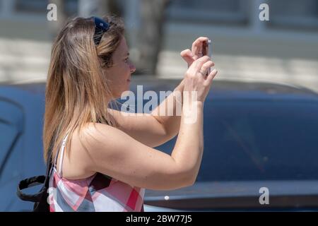 Saint John, NB, Canada - 25 maggio 2019: Una donna che scatta una foto utilizzando un cellulare in una giornata di sole. Foto Stock