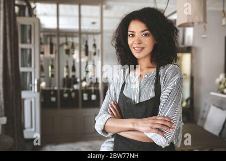 Ritratto di bella ragazza afroamericana che indossa camicia e grembiule nel ristorante Foto Stock