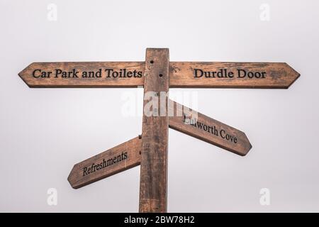 Un cartello su un palo di legno che indica le indicazioni per raggiungere i luoghi Foto Stock