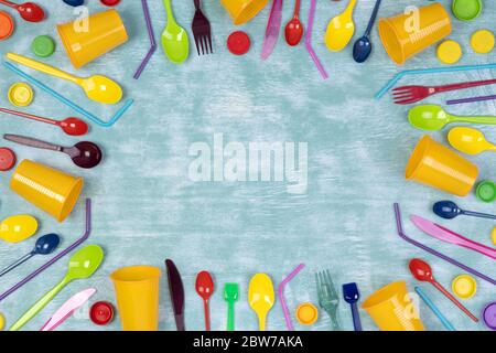 Oggetti monouso in plastica come tazze, forcelle e cucchiai e cannucce per bevande su sfondo blu, vista dall'alto Foto Stock