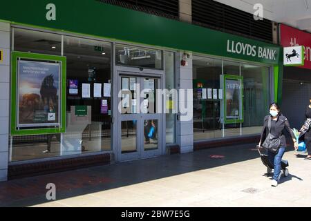 Wood Green, Londra, UK 30 maggio 2020 - UNA donna che indossa una faccia che copre cammina oltre un ramo della Lloyds Bank in Wood Green. Il governo ha annunciato un rilassamento delle regole di blocco COVID-19 da lunedì 1 giugno. Credit: Dinendra Haria/Alamy Live News Foto Stock