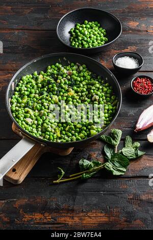 piselli con funghi al keto ingredienti in padella e piselli in ciotola con pepe di scalogno alla menta e vista sul piano del sale sul tavolo in legno del vecchio pub verticale. Foto Stock