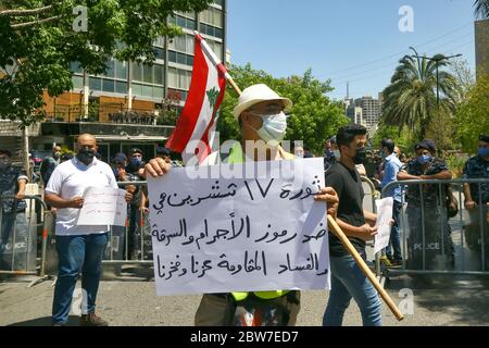 Beirut, Libano. 30 maggio 2020. Un sostenitore di Hezbollah pro-iraniano, porta un cartello con la scritta "la rivoluzione del 17 ottobre è contro la corruzione, ma la resistenza è la nostra dignità e orgoglio", durante una controricorrente contro gli attivisti anti-governo, che chiedono l'attuazione di varie risoluzioni del Consiglio di sicurezza delle Nazioni Unite, compreso il disarmo dei gruppi armati nel paese. Credit: Marwan Naamani/dpa/Alamy Live News Foto Stock