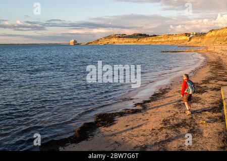 Persona sulla spiaggia a Colwell Bay con Fort Albert in lontananza, Isola di Wight, Inghilterra, Regno Unito Foto Stock