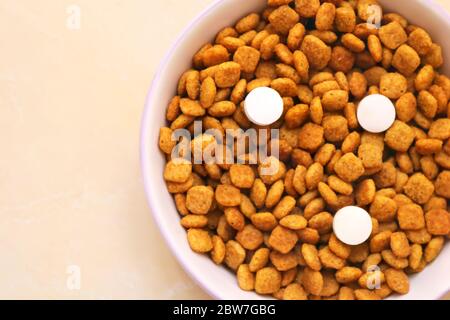 Cibo di gatto con tre pillole in una ciotola sul pavimento. Vitamine per i gatti. Trattamento Cat Foto Stock