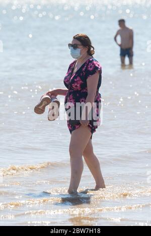 Una donna che indossa una maschera protettiva che si addica in mare a Southend-on-Sea in Essex, come si ricorda al pubblico di praticare la distanza sociale dopo il rilassamento delle restrizioni di blocco. Foto Stock