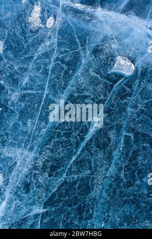 Modello di ghiaccio del lago e un piccolo ghiaccio fuso galleggia sullo sfondo. Bolle d'aria e incrinature. Incredibile modello invernale. Verticale. Foto Stock