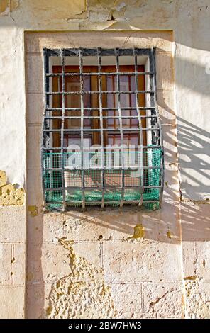 Vecchia griglia arrugginita fissata ad una finestra in un vecchio edificio a la Valletta, Malta Foto Stock