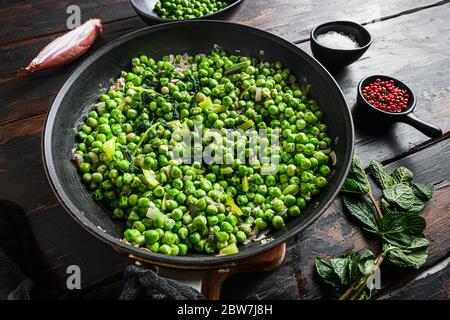 Piselli funghi ricetta senza glutine in padella e piselli in ciotola con pepe di scalogno di menta e vista laterale del sale sulla superficie di legno del vecchio pub primo piano nuovo largo A. Foto Stock