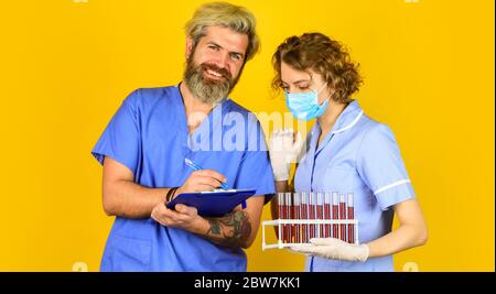 prendere appunti. i medici indossare maschera respiratore. infezione vaccino e sangue test. Medico di lavoro. Coppia medica uso di test di vaccinazione tubo. Dire no al coronavirus. Virus rimedio in laboratorio. Foto Stock